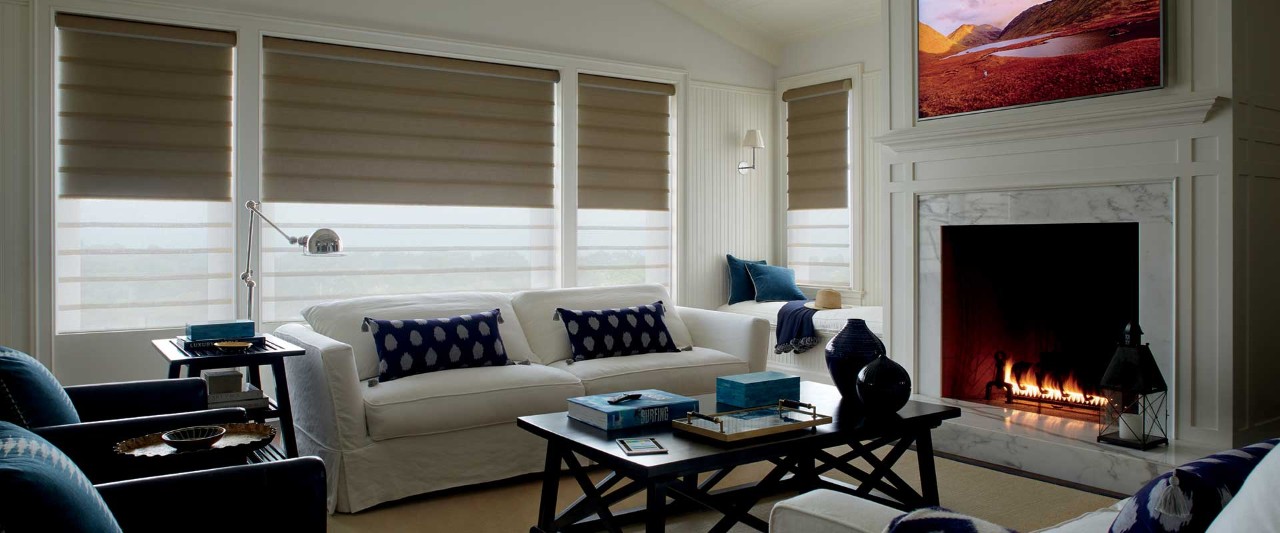 Family room with lit fireplace and duolite shades.